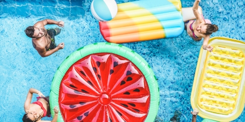 group of people in a swimming pool with rafts shaped like fruit